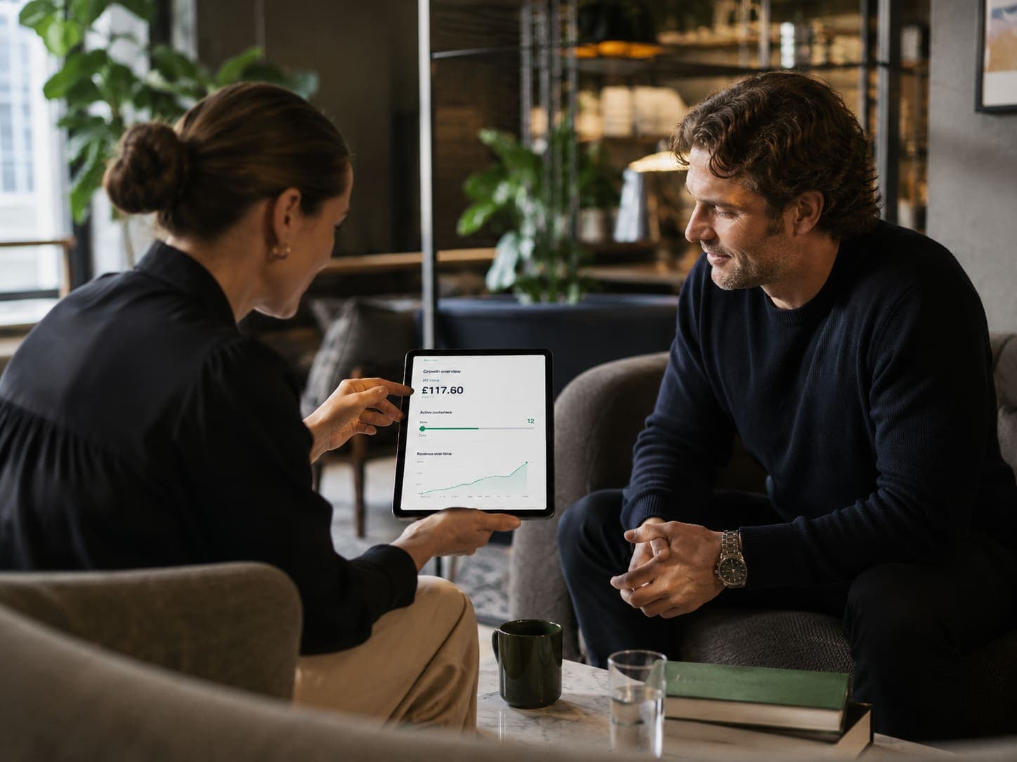 Two people reviewing a NegoTrack dashboard on a tablet in a lounge.